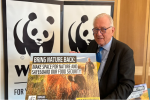 Sir Peter Bottomley in front of a WWF poster